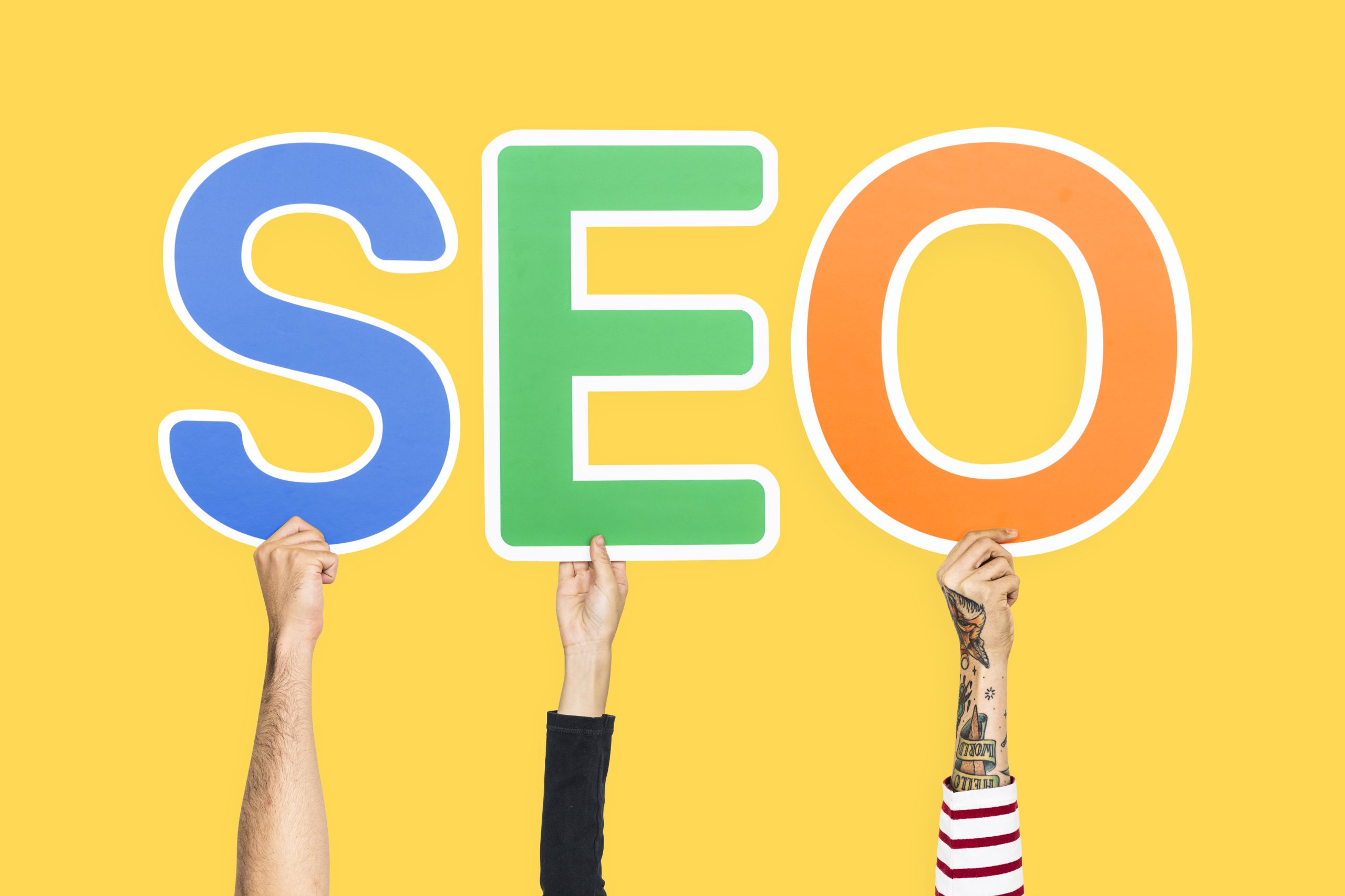 Hands holding up colorful letters forming SEO abbreviation.