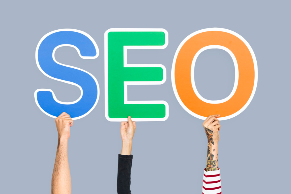 Hands holding up colorful letters forming SEO abbreviation.