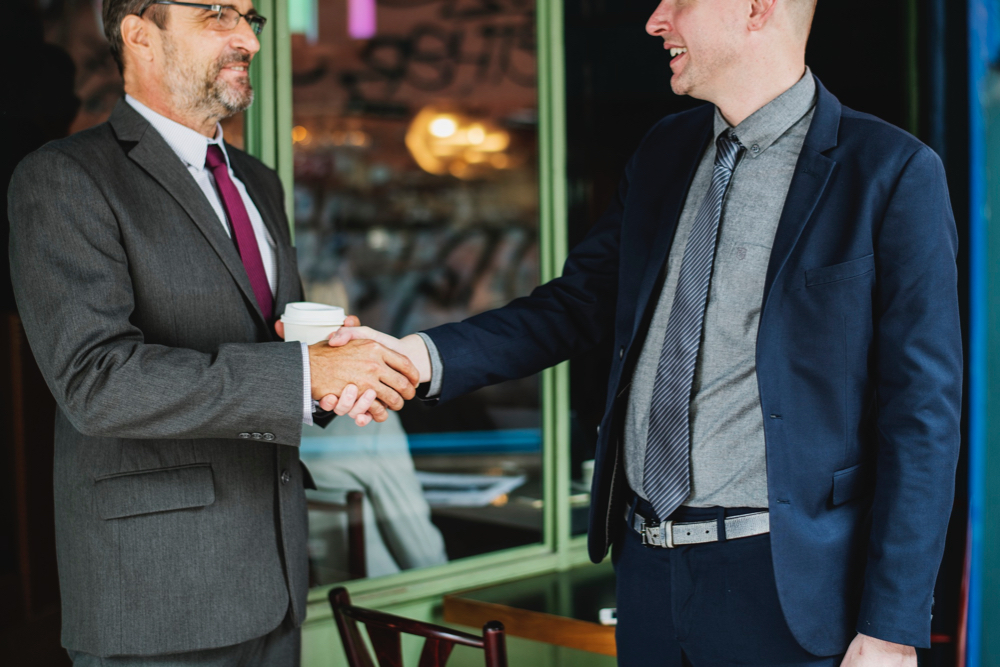 Two businessmen in suit, shaking their hands for enterprise business SEO growth campaign.