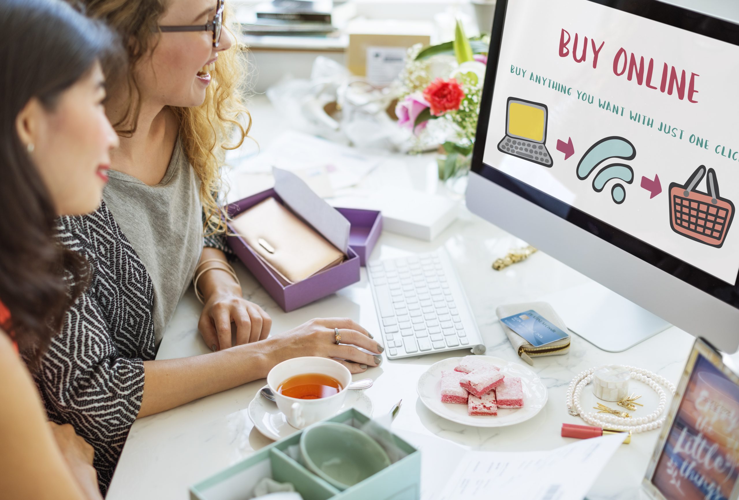 Two women doing some online shopping on their personal computer.