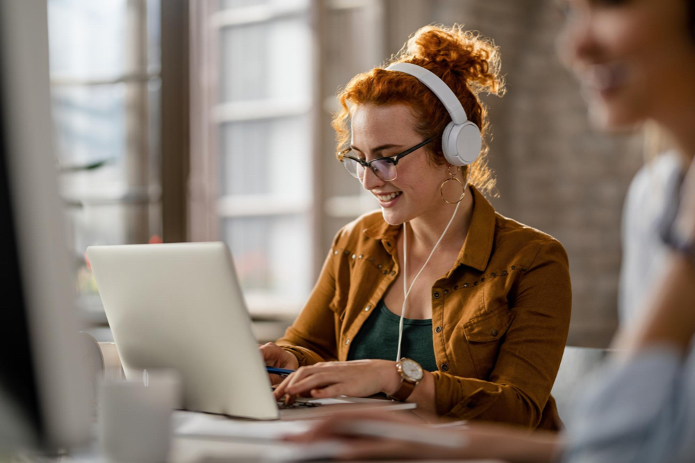 A blogger conceptualizing an SEO blog topic using a laptop, with head phones on.