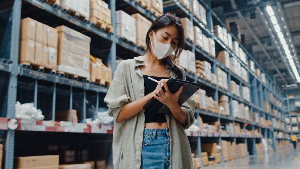 A retail store owner doing inventory inside a warehouse.