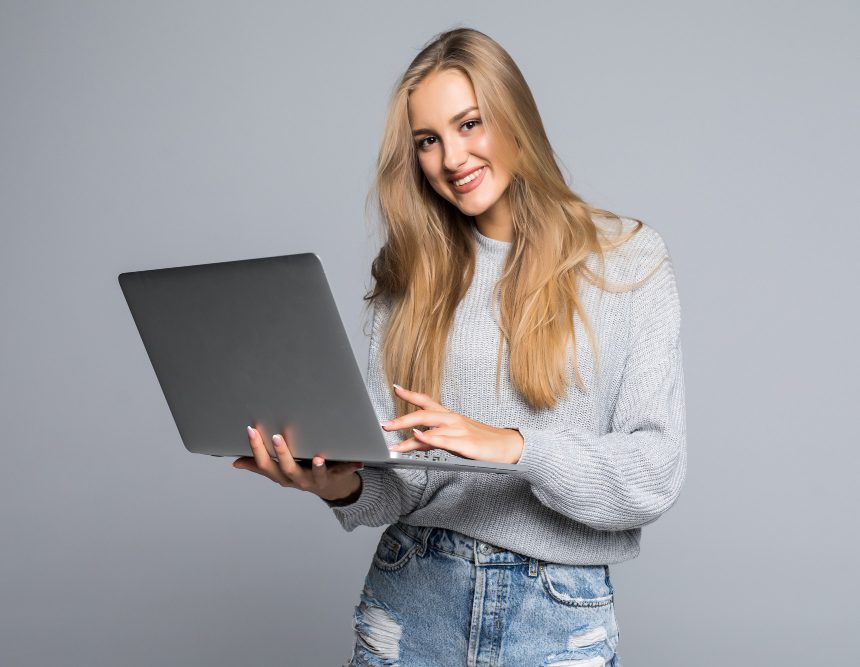 An SEO expert, in casual clothes, holding her laptop, posing a smile for the camera.