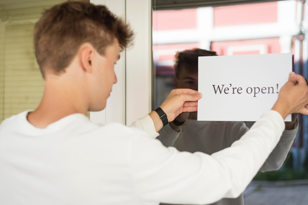 A staff posting a We're Open sign, keeping the business up to date.