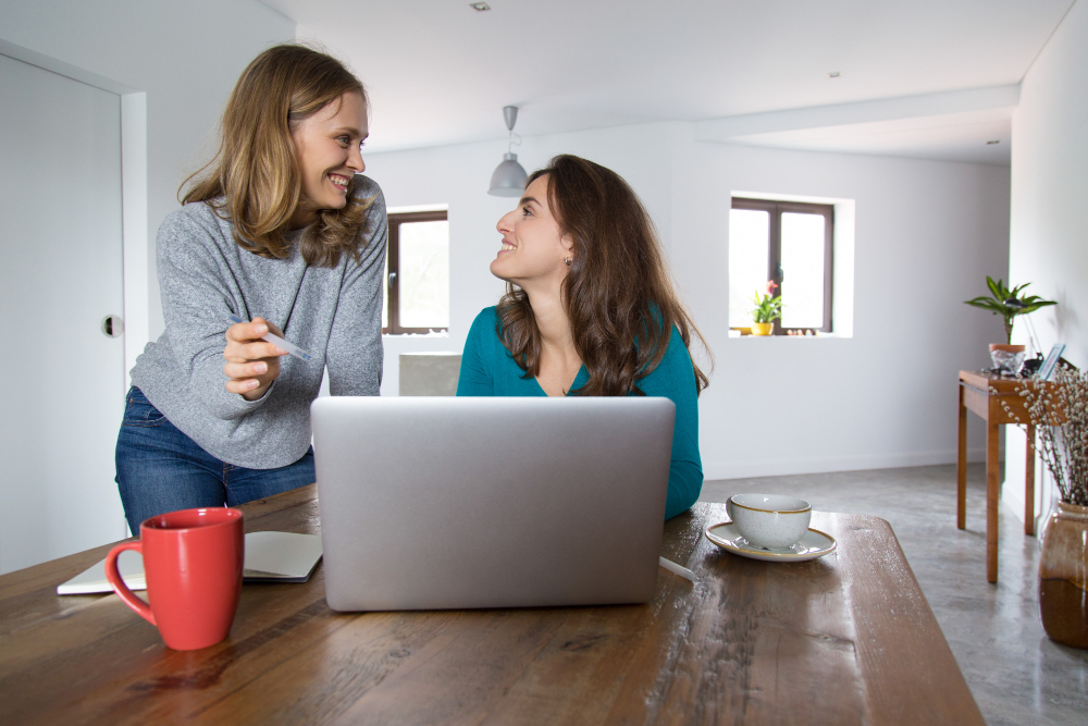 Interior designers, discussing about their home & decor website inside an open space room, with a laptop and red coffee on the side of the table.
