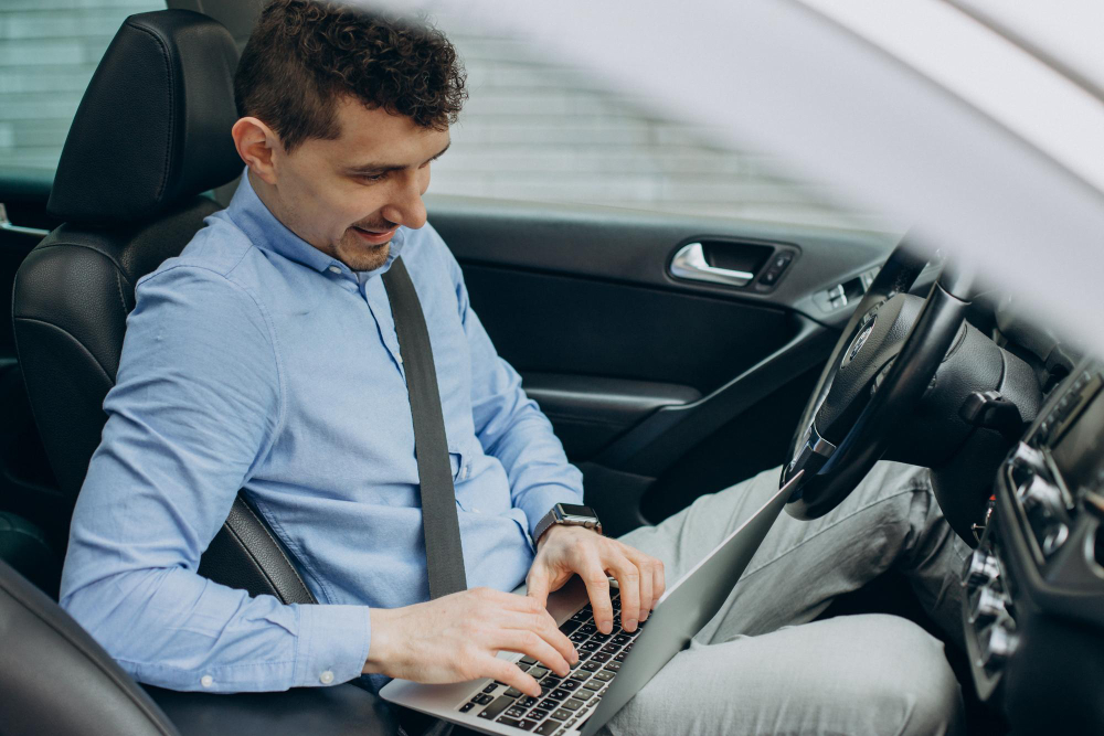 A marketing guy in casual business suite, working inside a car on on-page optimization for car dealership.