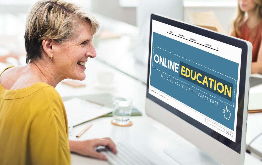 A senior educator checking on an online education website, using a laptop.