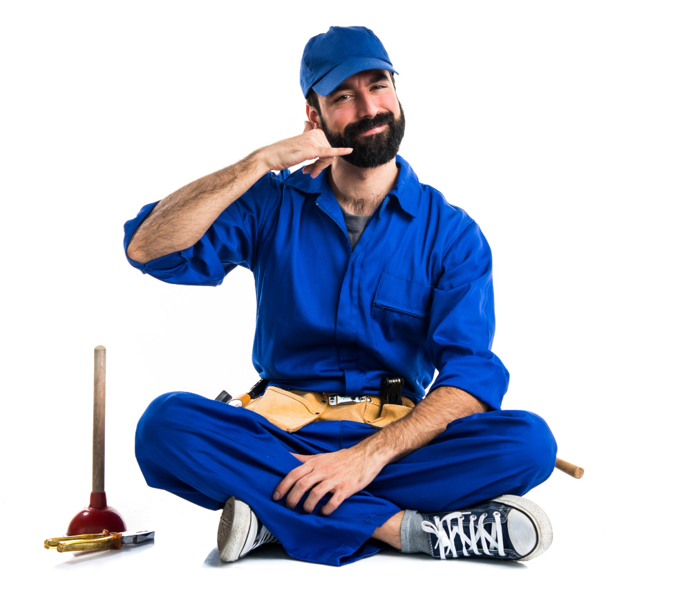 A plumber in blue onesie and blue hat, making a phone call sign, while squatting on the floor, with plumbing tool on the left side of the picture.