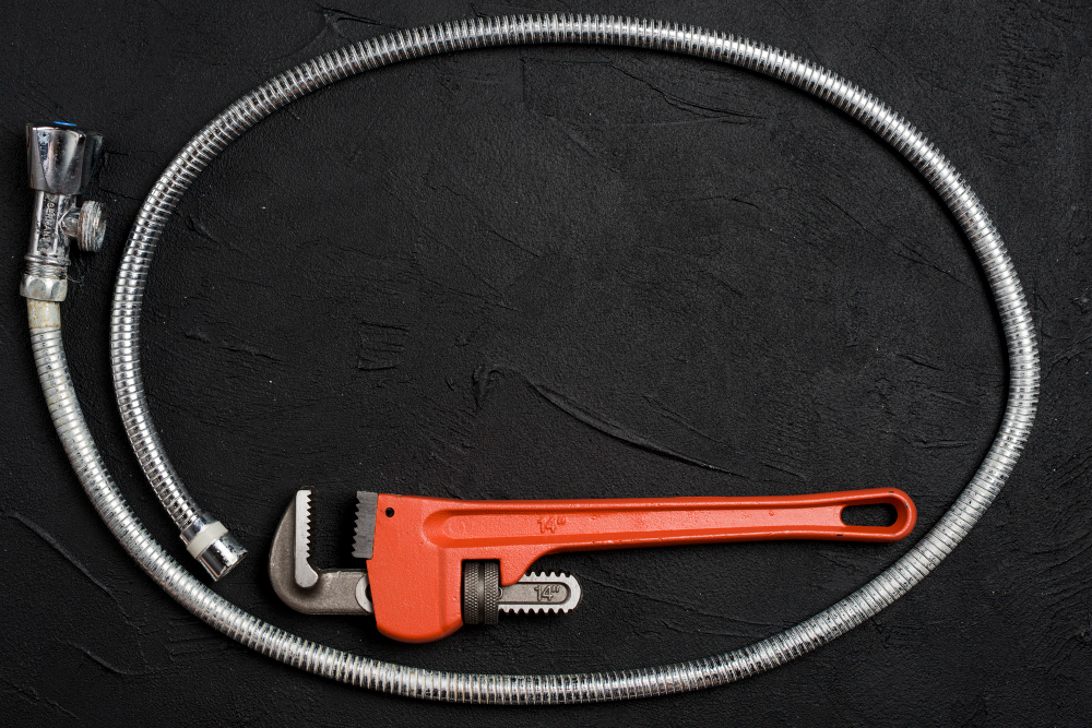 A shower hose circling a red plumbing tool in black background.